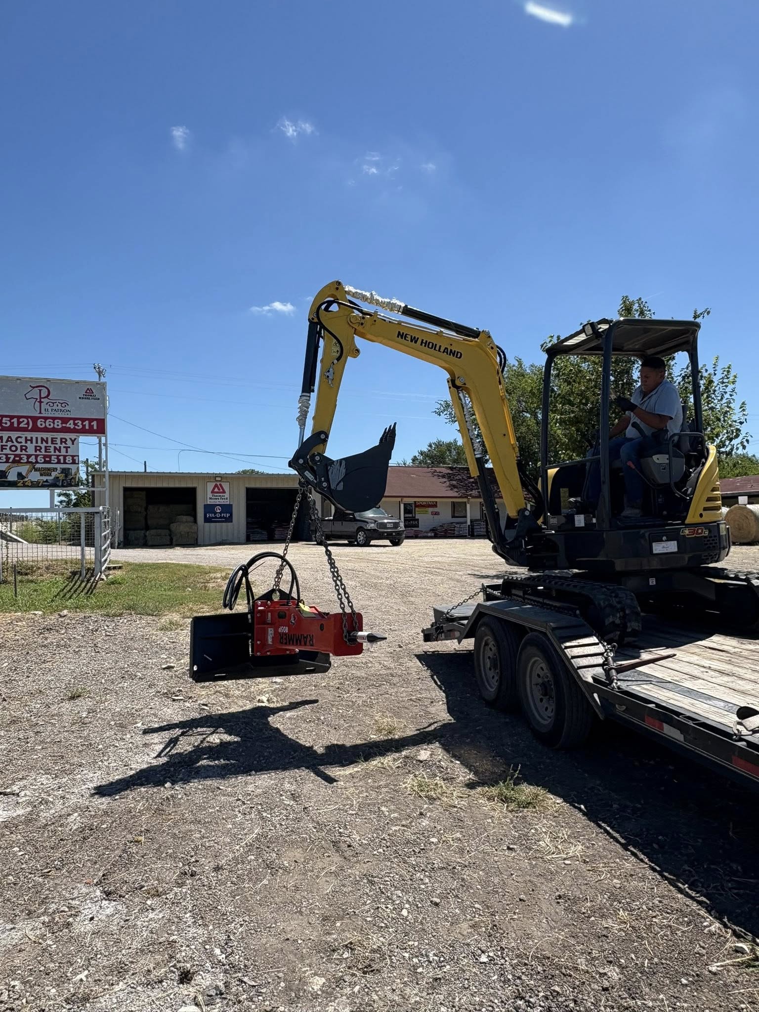 Mini excavator on flatbed — Machinery For Rent sign